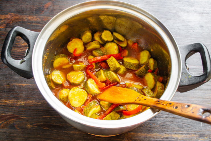 Cooking the salad until cucumbers change color. The cucumber salad simmering in the pot, with the cucumbers turning an olive green color.