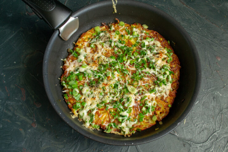 The final result: a perfectly cooked, golden, and crispy Royal Dranik. The finished royal potato pancake in the skillet, with melted cheese and a golden crust.