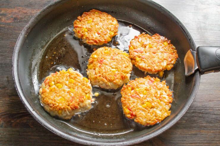 Cooking Patties to Golden Perfection Crab stick patties frying in a pan, showing a golden-brown crust on one side.
