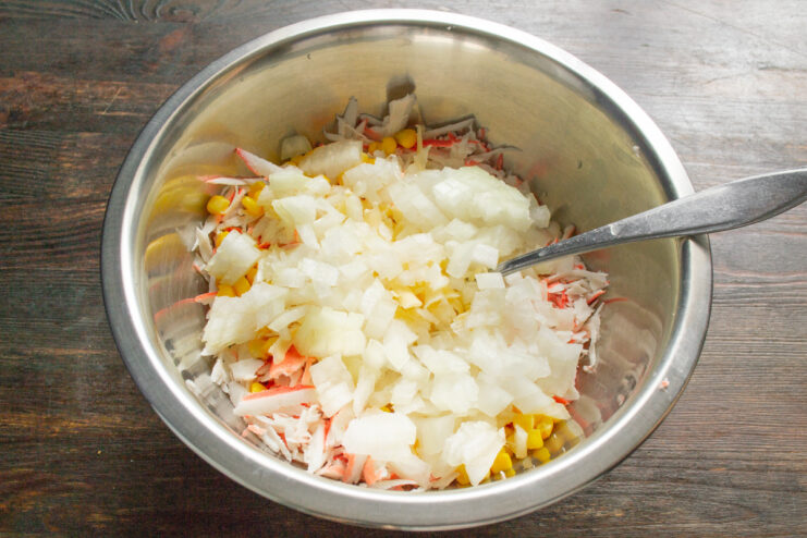 Adding Finely Diced Onion Finely chopped onion being added to the crab stick and cheese mixture in a bowl.
