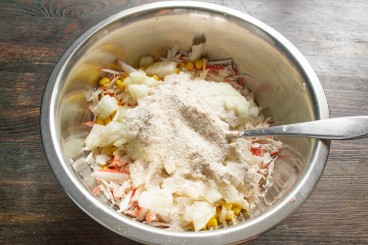 Using Rice Flour as a Binder Adding homemade rice flour to the bowl with the crab stick patty mixture.