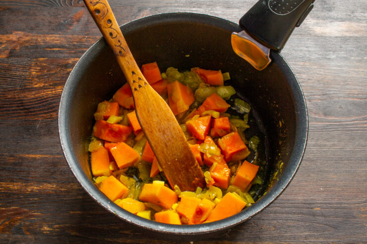 Sautéing pumpkin and onion together to deepen their flavors. Diced pumpkin and onion being sautéed in a pan.