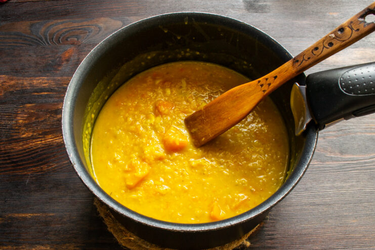 Simmering the soup ingredients until the pumpkin and lentils are tender. Pumpkin and lentil soup simmering in a covered pan on the stove.