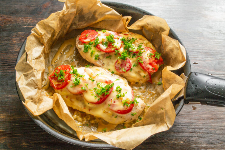 Garnishing with Fresh Parsley Before Serving Finished pan-fried chicken with tomato and cheese, garnished with fresh parsley.