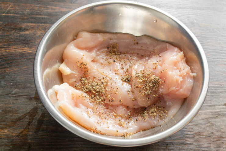 Seasoning the Chicken Breast Before Cooking Raw chicken fillets being seasoned with salt and freshly ground pepper.