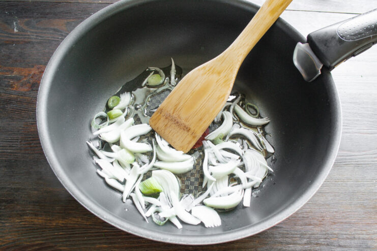 Sautéing Onions to Build a Flavor Base Chopped onions being sautéed in a hot wok with oil.