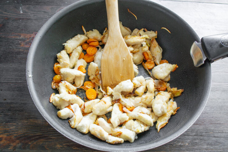 Stir-Frying Chicken and Vegetables Over High Heat Chicken and vegetables being stir-fried together in a wok over high heat.