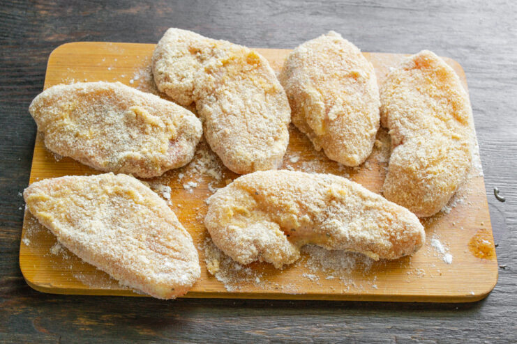 Step-by-Step Breading Process for Chicken Fillets A piece of chicken fillet being coated in breadcrumbs, with bowls of flour and egg nearby.