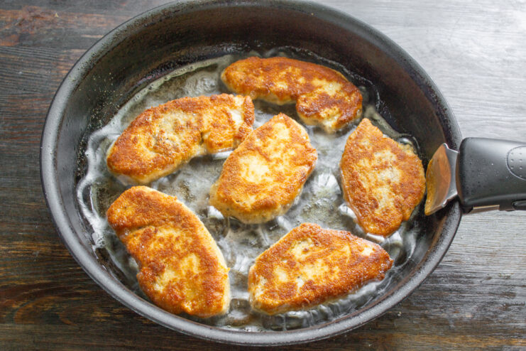 Frying Breaded Chicken Fillets Until Golden Breaded chicken fillets frying to a golden brown in a hot pan.