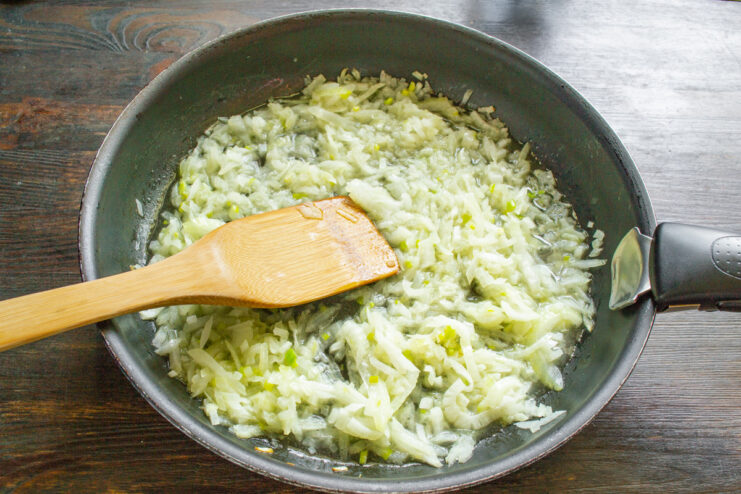 Sautéing Chopped Onions Until Golden Chopped onions being sautéed in a frying pan.
