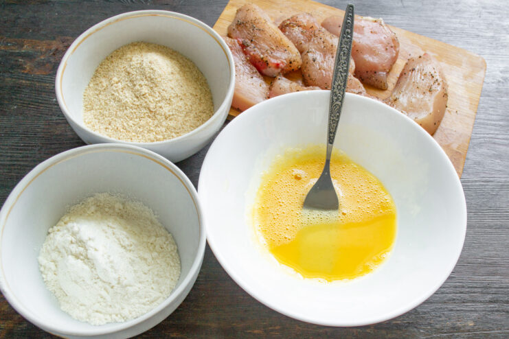 Setting Up the Breading Station for Chicken Three bowls set up for breading: one with flour, one with a beaten egg, and one with breadcrumbs.