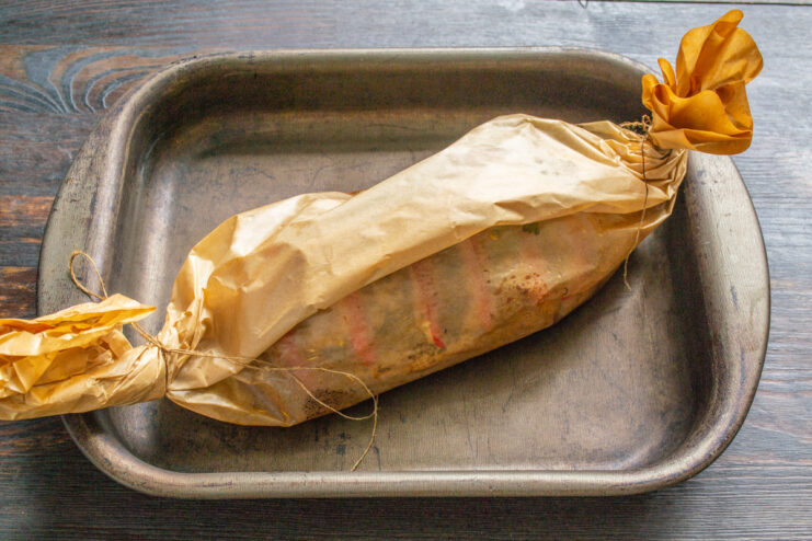 The Unique Baking and Resting Method for Juicy Chicken The parchment envelope with chicken baking on a sheet in a hot oven.