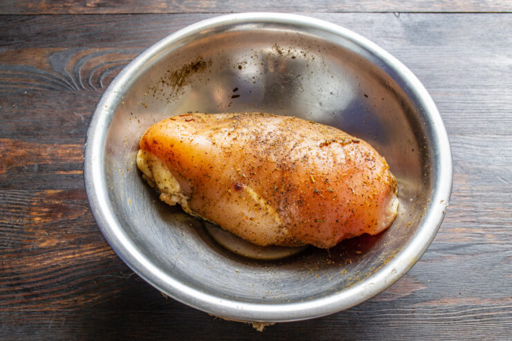 Step 1: Marinating the Chicken Fillet with Spices Raw chicken fillet being rubbed with salt, curry powder, and black pepper.
