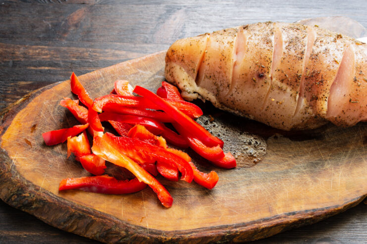 Preparing the Bell Pepper for the Chicken Filling Slicing a red bell pepper into long, thin strips on a cutting board.