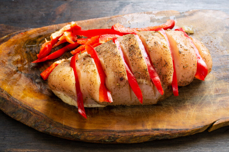 Stuffing the Chicken Fillet with Bell Pepper Strips Strips of red bell pepper being inserted into the cuts made in the chicken fillet.