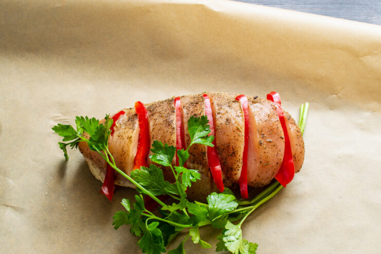 Adding Fresh Herbs for Extra Flavor - Parsley, Cilantro, or Dill Fresh parsley sprigs being added on top of the chicken fillet before wrapping.