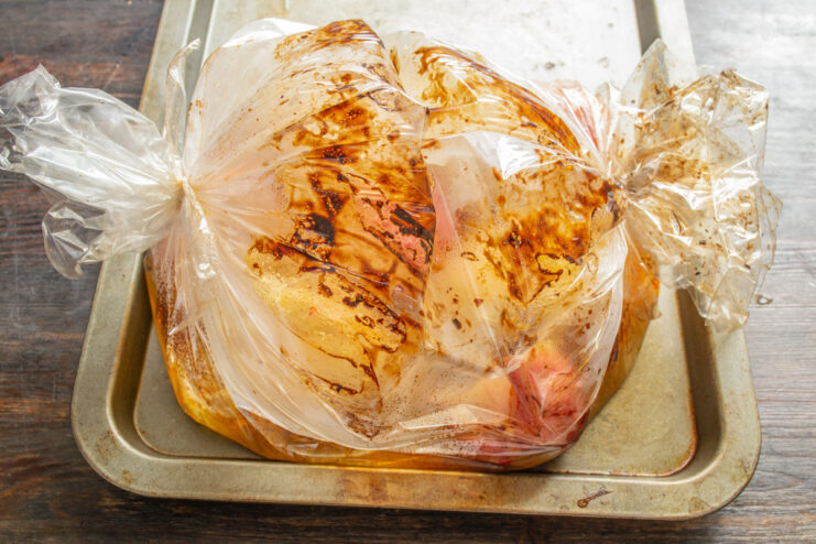 Step 9: Baking the Chicken to Perfection in the Oven A baking sheet with the sealed roasting bag of chicken being placed in an oven.