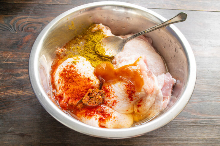 Step 3: Creating the Sweet and Savory Honey Marinade Pouring honey and apple cider into a bowl with seasoned chicken thighs.