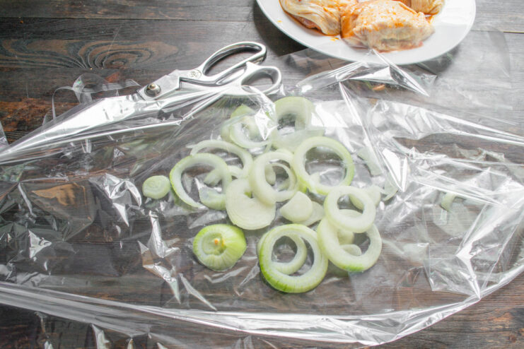 Step 5: Preparing the Roasting Bag with an Onion Base Sliced onion rings arranged in a single layer inside a clear roasting bag.