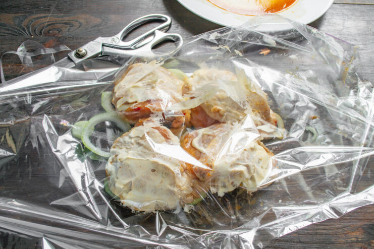 Step 6: Arranging the Marinated Chicken in the Bag Marinated chicken thighs placed over onions in a roasting bag, being topped with mayonnaise.