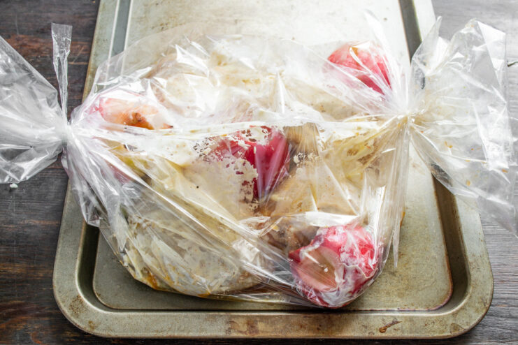 Step 8: Sealing the Roasting Bag Before Baking The ends of a roasting bag filled with chicken and apples being tied shut.