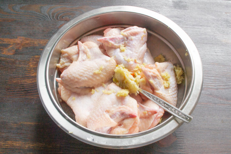 How to Prep Chicken Wings for Roasting Raw chicken wings being rinsed with cold water in a metal kitchen sink.