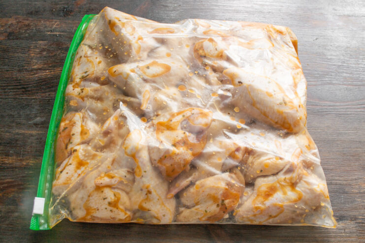 Marinating the Wings for Maximum Flavor Chicken wings in a honey-soy marinade being sealed in a clear zip-lock bag.
