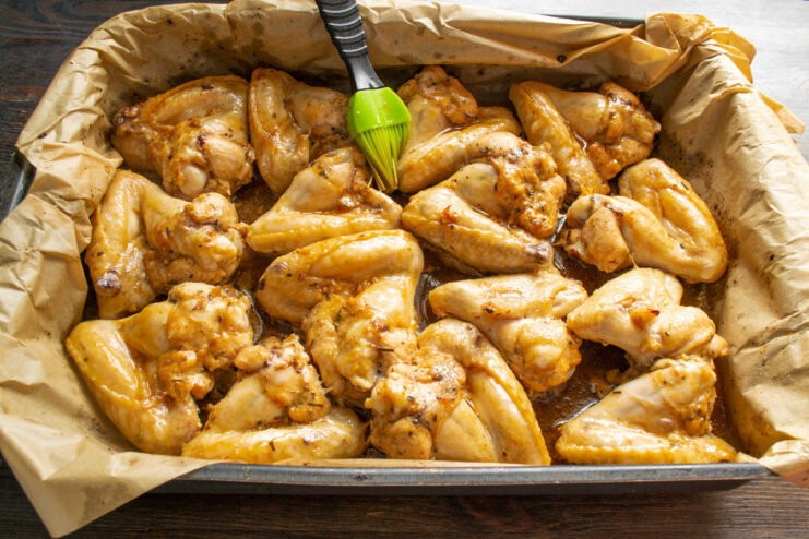 Baking the Chicken Wings to Golden Perfection A baking sheet with honey-marinated chicken wings being placed into a hot oven.
