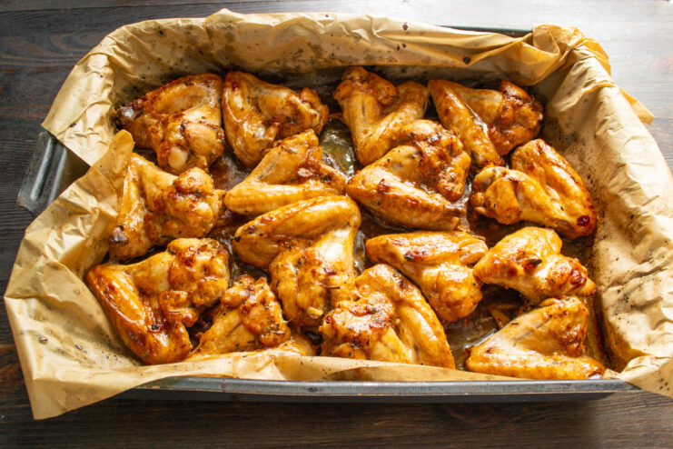 A Simple Trick to Prevent Burning Golden-brown baked chicken wings on a baking sheet, with some liquid marinade at the bottom.