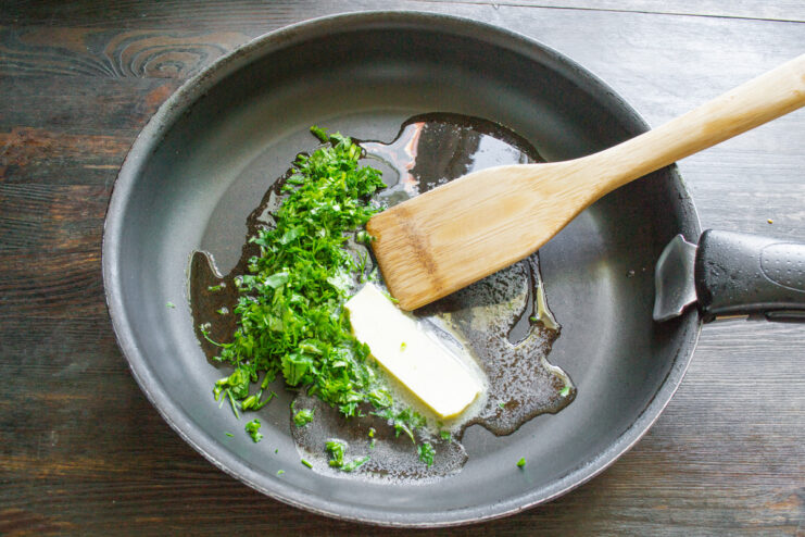 Making the Cilantro Butter Sauce Melting butter with chopped fresh cilantro in a skillet to create a sauce.