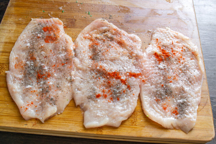 Seasoning the Chicken Schnitzels Seasoning flattened chicken cutlets with salt, black pepper, and red pepper.