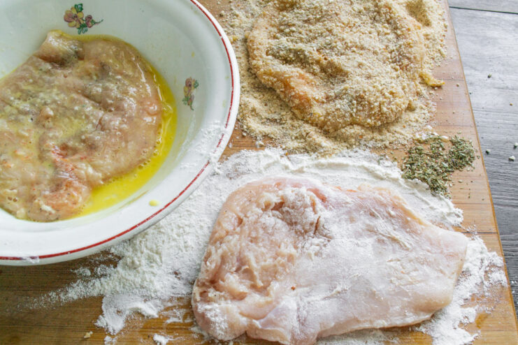 Breaded Chicken Schnitzel Ready for Frying A perfectly breaded raw chicken schnitzel resting on a cutting board.