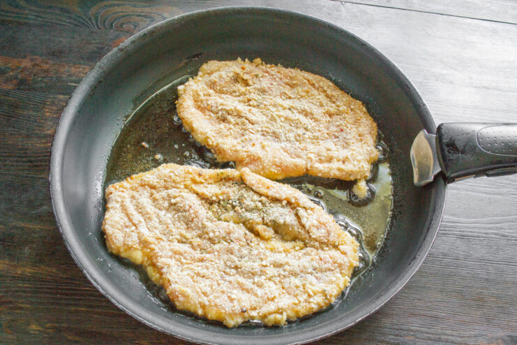 Heating Oil in a Pan for Frying Schnitzels Pouring vegetable oil into a large skillet to heat it up for frying.