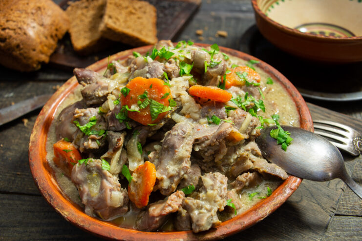 A white bowl filled with Italian-style chicken gizzards stew, garnished with fresh parsley.
