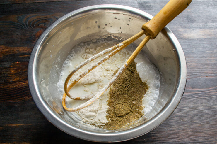 Preparing the creamy smetana sauce for the gizzards. A white bowl with smetana, flour, and spices being mixed for the sauce.