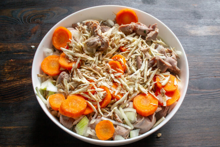 Adding grated celeriac for a unique, earthy flavor. Grated celery root being added to the mix of gizzards and vegetables in the dish.