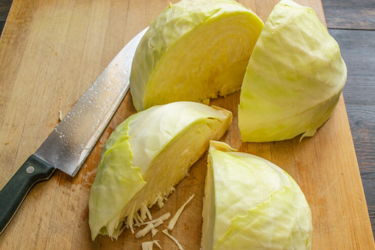 Step-by-step: How to core a cabbage for fermenting A head of white cabbage cut into quarters with the core being removed.
