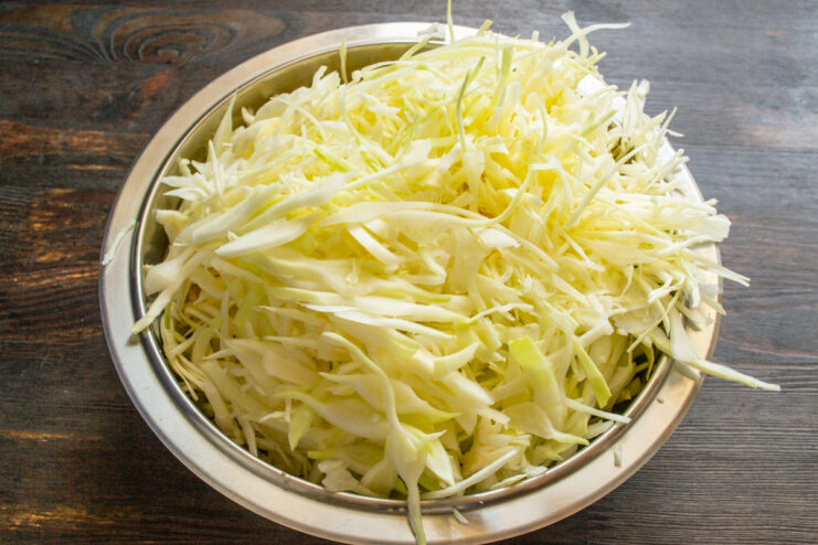 Shredding cabbage thinly is key for a good texture A close-up of thinly shredded white cabbage in a large bowl.