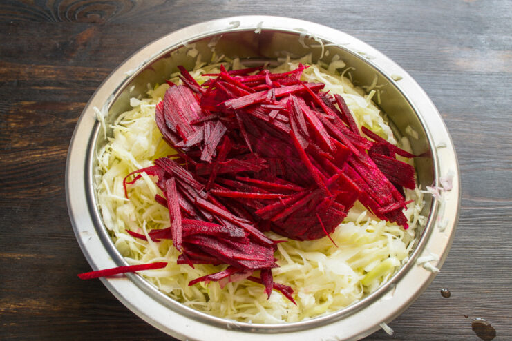 Julienning beets for color and flavor in fermented cabbage Peeled beets being cut into thin julienne strips on a cutting board.