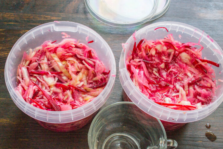 Packing the jars for fermentation without compacting A glass jar being filled loosely with the cabbage and beet mixture for fermentation.