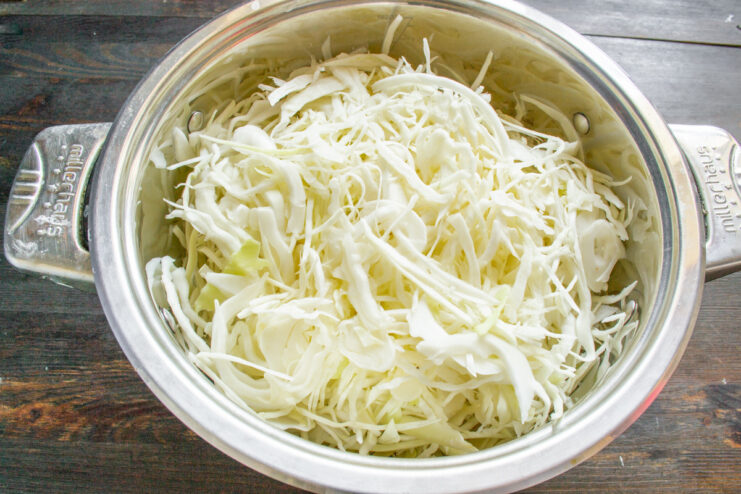 First Step of Fermentation: Placing Cabbage in a Pot A large pot filled with freshly shredded white cabbage.