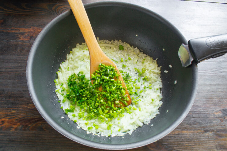 Starting the Bolognese sauce with onions and celery Finely chopped onion and celery being added to a hot skillet.