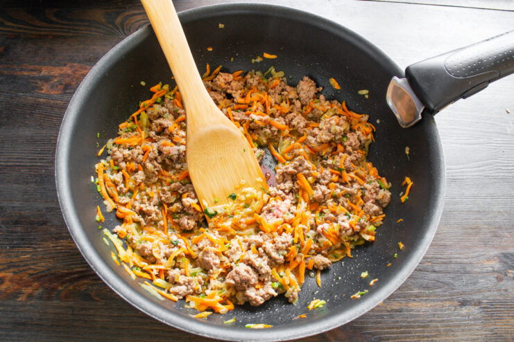 Deglazing the pan with white wine and herbs Pouring white wine into the skillet with ground meat and vegetables for the Bolognese sauce.