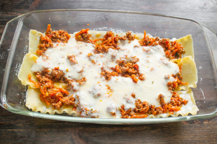 Assembling the lasagna layers in a baking dish Assembling the lasagna in a baking dish with layers of pasta, Bolognese, and béchamel sauce.
