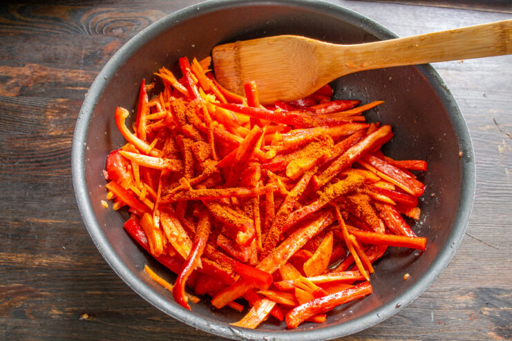 Adding Paprika for Flavor and Color Sprinkling bright red sweet paprika powder into the vegetable stew.