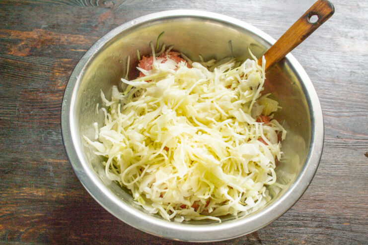 How to Finely Shred Cabbage for the Perfect Texture Hands finely shredding white cabbage on a cutting board.