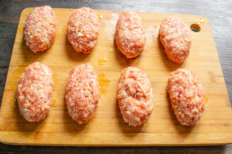 Shaping the Lazy Cabbage Rolls into Patties Shaped oval patties of the lazy cabbage roll mixture on a wooden cutting board.