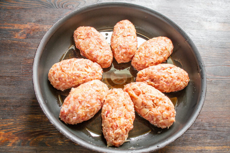 Arranging the Cabbage Rolls in a Pan Before Cooking Lazy cabbage roll patties arranged in a black skillet, ready for the sauce.