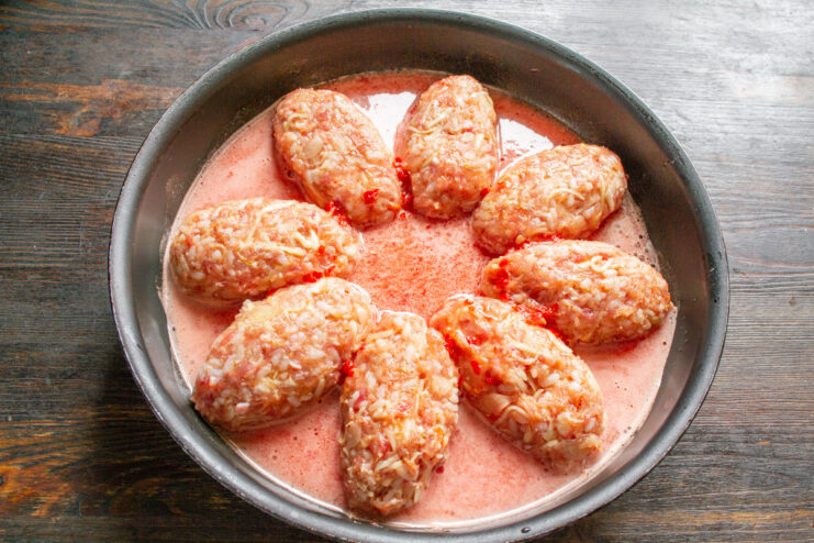 Pouring Homemade Tomato Sauce Over the Cabbage Rolls Pouring fresh tomato sauce over the uncooked lazy cabbage rolls in a skillet.