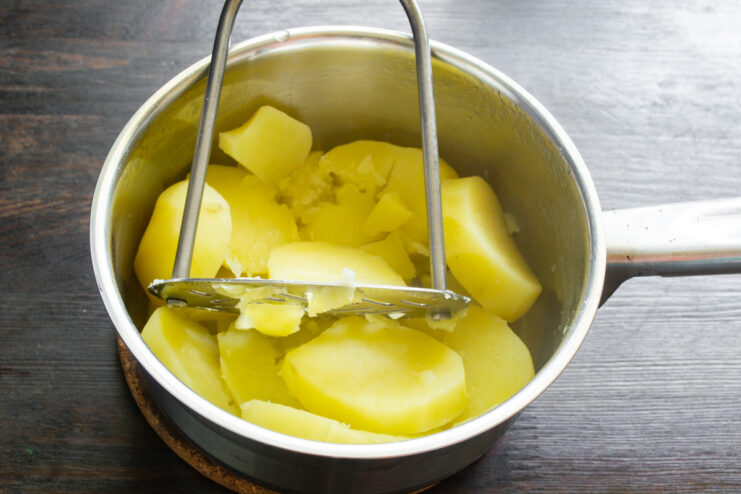 Step-by-step: Preparing the potato dough for lazy varenyky. A bowl of mashed potatoes next to an egg, flour, and melted butter, the ingredients for the lazy varenyky dough.